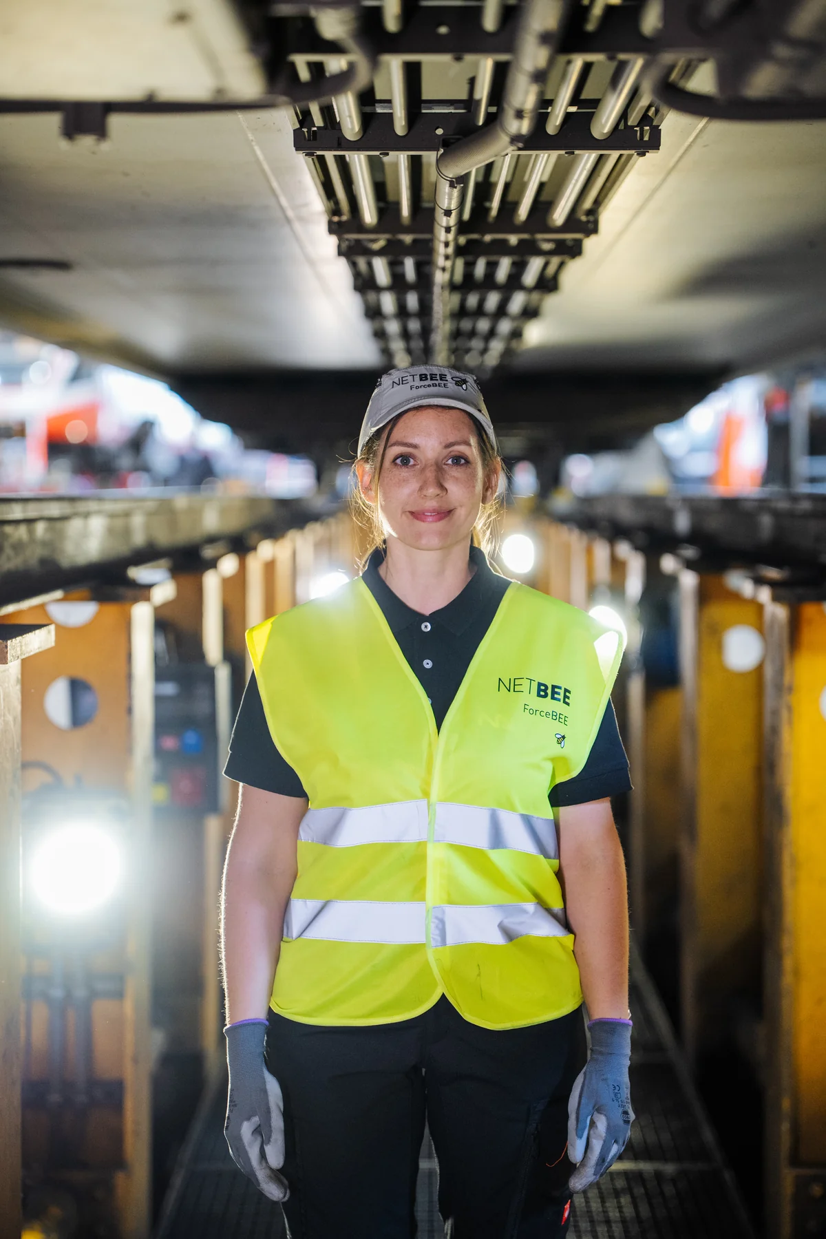 Mitarbeiterin mit ForceBEE-Sicherheitsweste im Prüfgraben unter einem Schienenfahrzeug